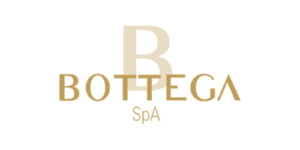 โลโก้ Bottega SpA สีเหลืองบนพื้นหลังโปร่งใส มีตัวอักษร B ขนาดใหญ่สลับกับคำว่า Bottega ในแบบอักษรที่หรูหรา ชวนให้นึกถึงฉลากไวน์ชั้นเลิศ.